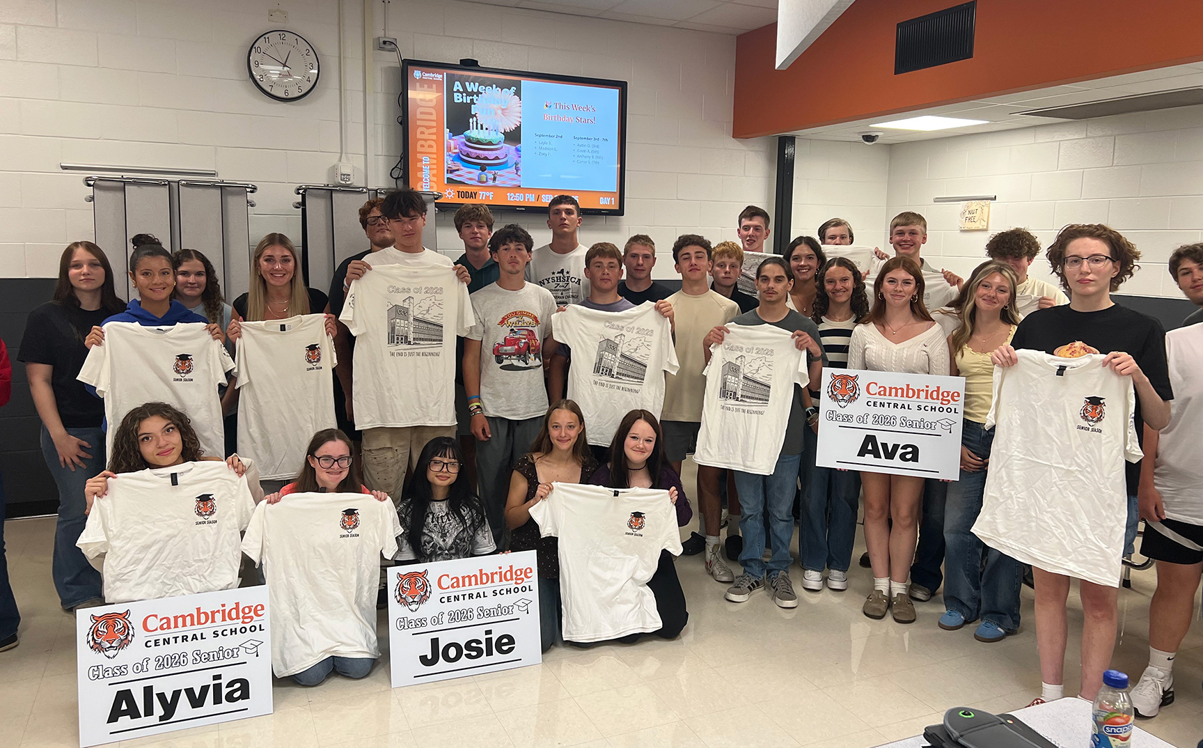 Class of 2026 students posing with lawn signs and t-shirts