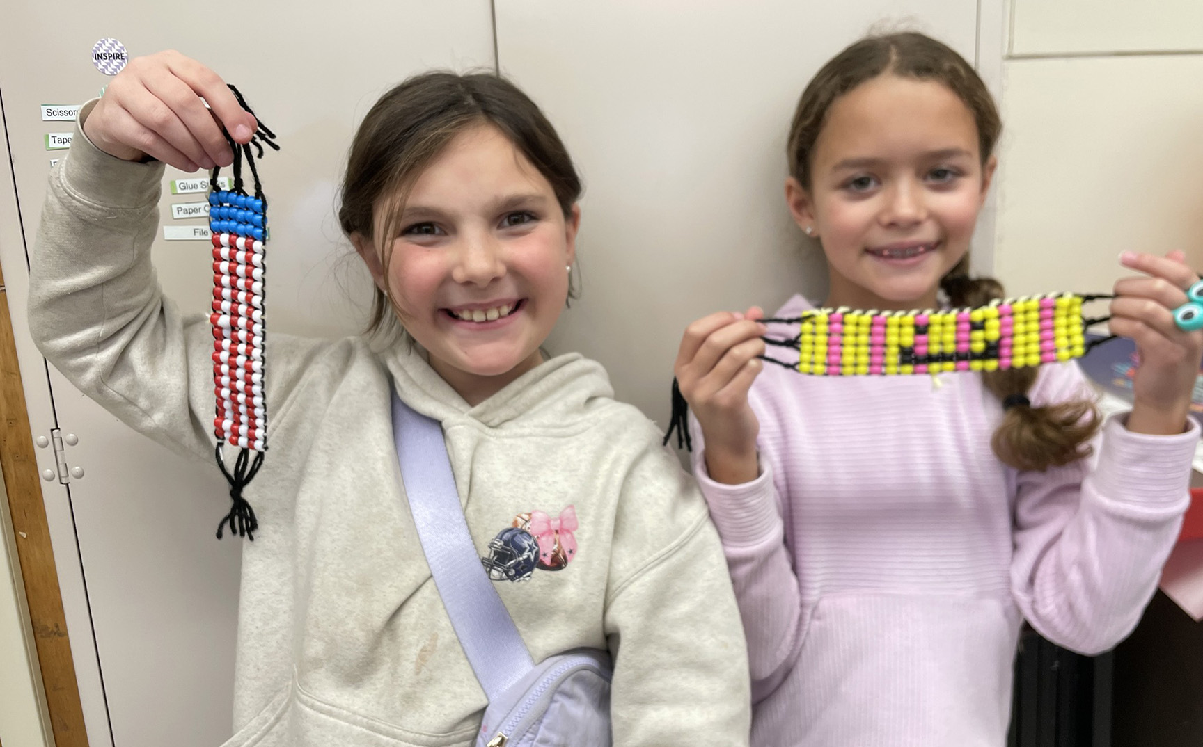 Elementary students holding up their art project