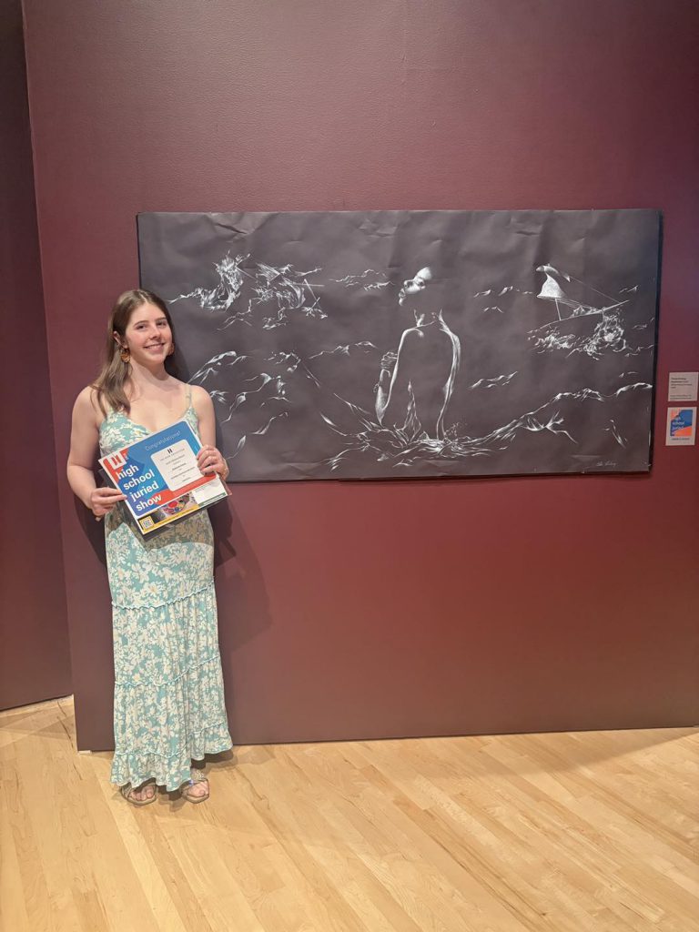 Estella Kvinlaug posing in front of her artwork, Suppression