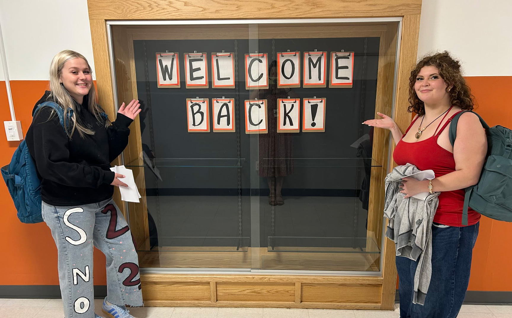 High school students posing at a display case with a welcome back poster